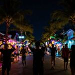 Seminyak nightlife with dancing silhouettes and neon lights.