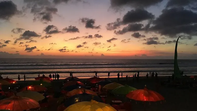 Sunset over Seminyak beach with beach-club umbrellas
