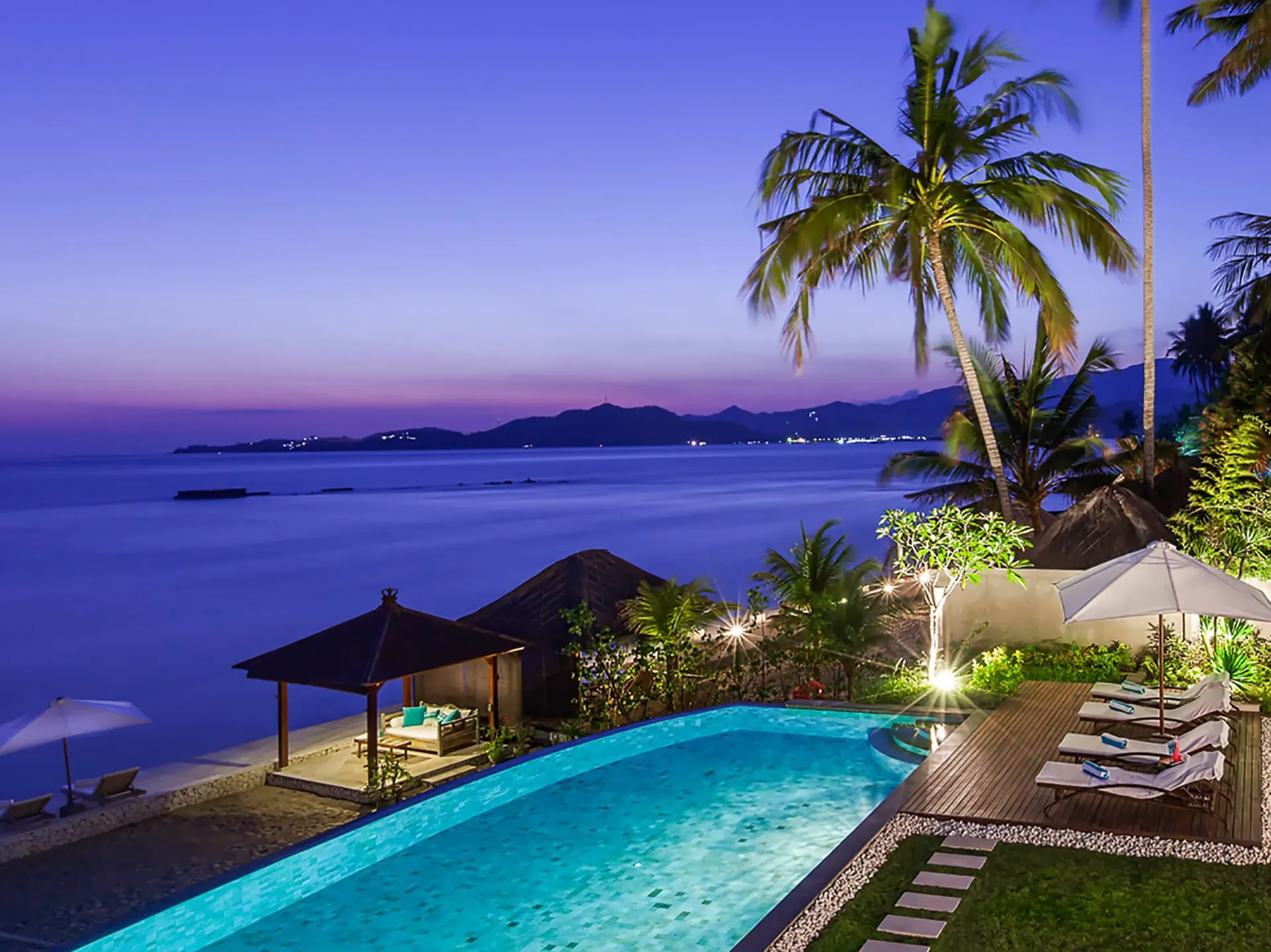 Infinity pool of a private villa at dusk, looking out over the sea in East Bali
