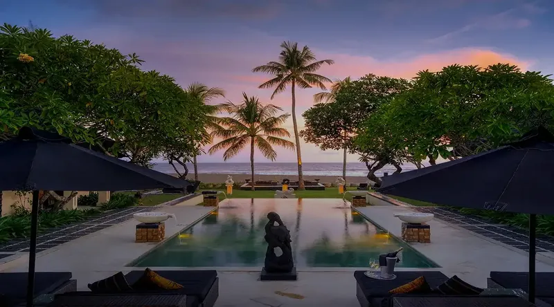 Villa pool lit at dusk with garden pavilion, Bali